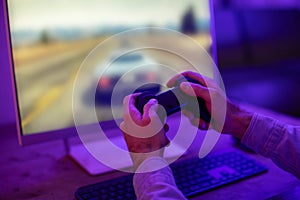 Hands holding a game controller before a screen