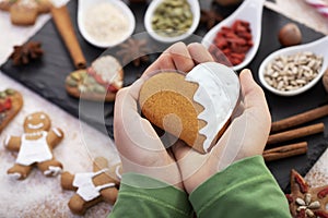 Hands holding gingerbread heart with white frosting - love christmas food concept