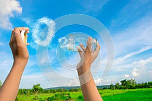 Hands holding glass jar for keeping fresh air, O2 cloud word with a blue sky in the background