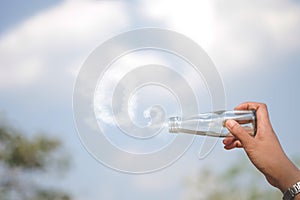 Hands holding glass jar for keeping fresh air, O2 cloud word with a blue sky in the background. concept of clean atmosphere, fresh