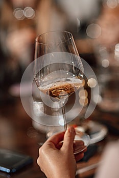 Hands holding a glass of wine close-up in a bar