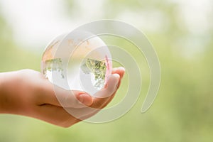 Hands Holding Globe Glass In Green Forest