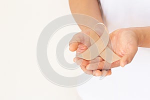 Hands holding gold ribbon on white background with copy space. The international awareness symbol for Childhood Cancer. World