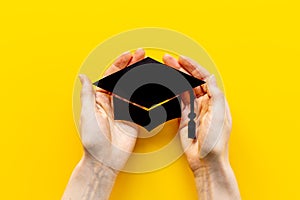 Hands holding graduation hat or academic cap paper cut. Education concept