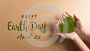 Hands holding green heart on brown background. World environment day, earth day and save earth concept