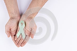 Hands holding green ribbon. White background