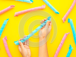 Hands holding hair curlers  on yellow background