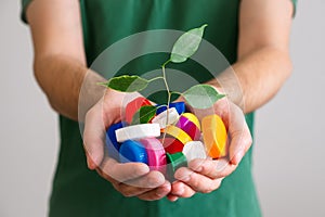 Hands holding a handful of colorful plastic lids with green leaves