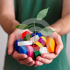 Hands holding a handful of colorful plastic lids with green leaves