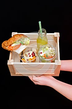 Hands holding healthy food box, menu with microgreens. Vegetarian sandwiches with micro greens assortment. Vegan party