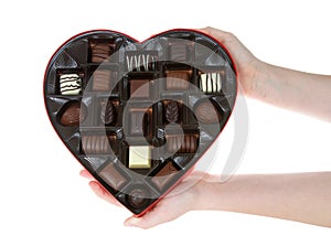 Hands holding heart box with chocolate candies, isolated