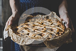 Hands holding homemade delicious apple pie. Close up