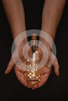 Hands holding an illuminated bottle
