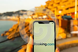 Hands holding iPhone 11 with an app of booking.com service.