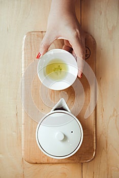 Hands holding Japanese Sencha Tea in clay pot