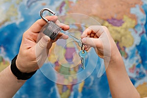 Hands holding keys and unlocking padlock