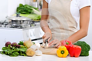 Hands holding knife cutting vegetables