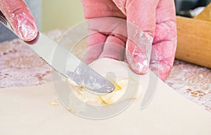 Hands holding knife spreading fresh butter on pastry - close view