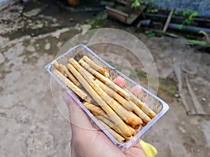 Hands holding light snacks, namely crunchy sticks, savory taste