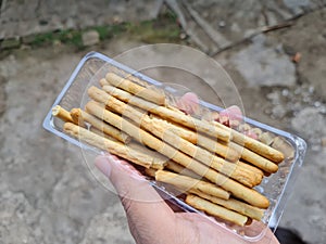 Hands holding light snacks, namely crunchy sticks, savory taste