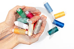 Hands holding a lot of colorful coils of thread close up, white background - hobby and DIY such as dressmaking ebroidery and