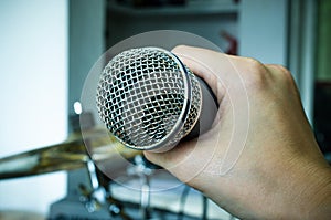 Hands holding a microphone in music room