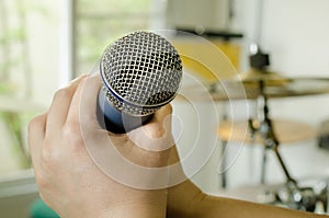 Hands holding a microphone in music room