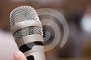 Hands holding microphones for speaking in seminar room