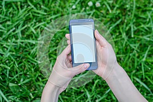 Hands holding mobile phone with empty screen over grass background cell phpne cellphone smart smartpohne mobile sms message typing