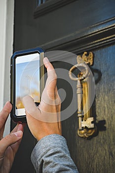 hands holding a mobile phone photographing a door knocker