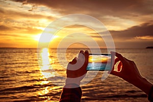 Hands holding mobile phone at sunset