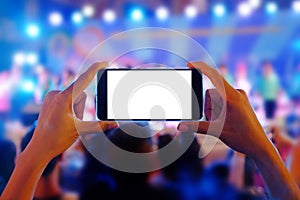 Hands holding a mobile smartphone records colorful live concert with blank white screen