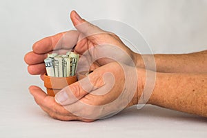 Hands holding money in a terracotta pot