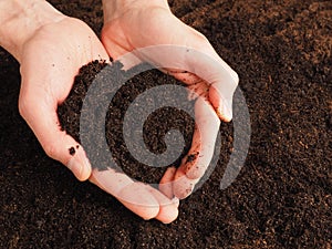 Hands holding nutrient-rich soil in the shape of a heart