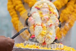 Hands Holding or offering incense or agarbatti stick in front of lord vinayaka or Ganesha while praying or worshiping