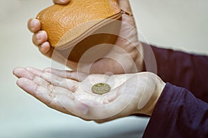 Hands holding one dollar coin and small money pouch photo