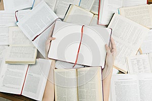 Hands holding opened notebook Among many books.