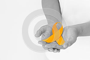 Hands holding orange color ribbon on  black and white with copy space. Kidney Cancer Awareness, Leukemia disease, Skin cancer