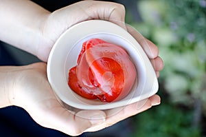 Hands holding organic red peppers in a ceramic pot.