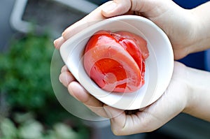 Hands holding organic red peppers in a ceramic pot.