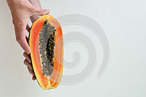 Hands holding a papaya slice.