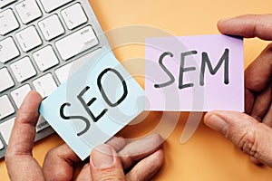 Hands holding cards with SEO and SEM photo