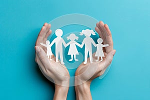 Hands holding paper cut outs of family
