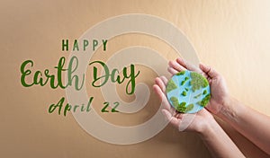 Hands holding paper earth with grass on brown background. World environment day, earth day and save earth concept