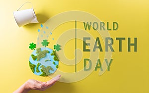 Hands holding paper earth with tree on yellow background. World environment day, earth day and save earth concept