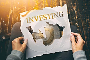 Hands holding a paper with the word investing written on it