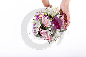 Hands holding a pastel bouquet from pink and purple gillyflowers and alstroemeria on white