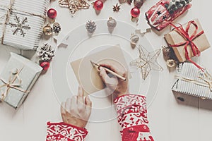 hands holding pencil and writing a letter wish list to santa claus with space for text. merry christmas and happy new year. child