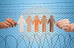 Hands holding people pictogram over barb wire