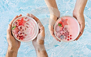 Hands Holding Pink Berry Yogurt Smoothie Bowls